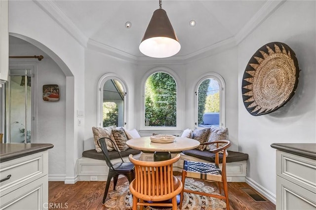 dining room featuring dark wood-type flooring, ornamental molding, breakfast area, and plenty of natural light