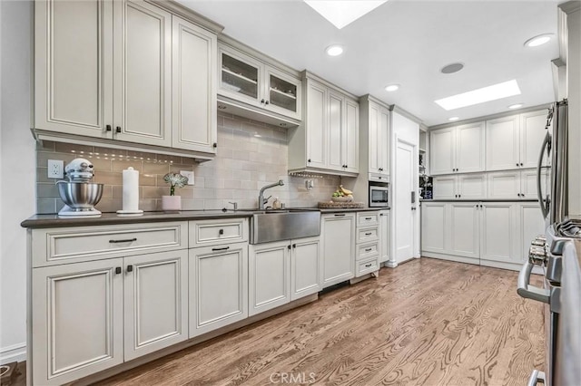 kitchen featuring dark countertops, a skylight, and a sink