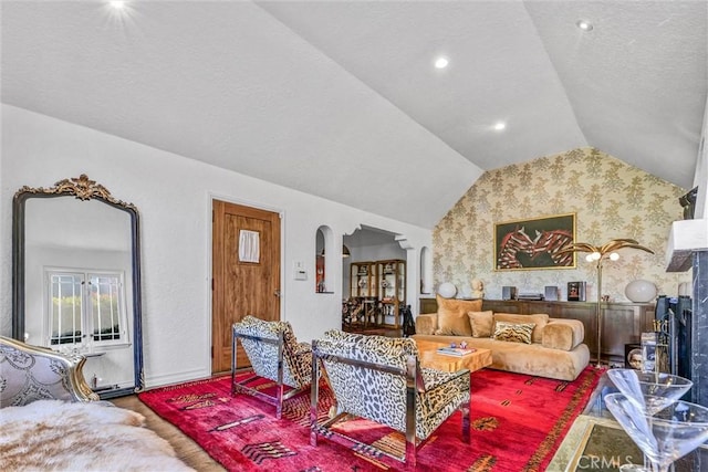 living area with wallpapered walls, arched walkways, vaulted ceiling, and recessed lighting