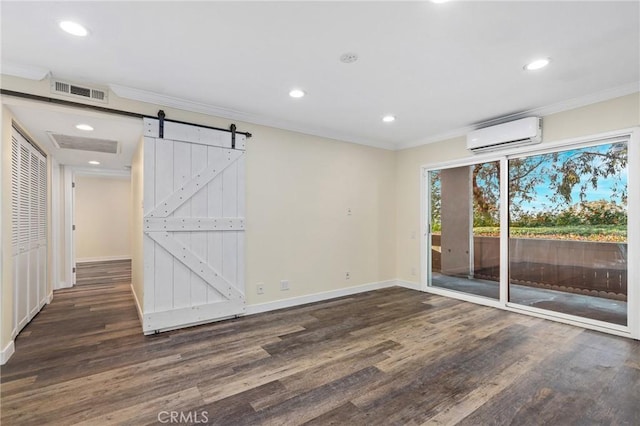 empty room with dark wood-type flooring, crown molding, a barn door, and an AC wall unit