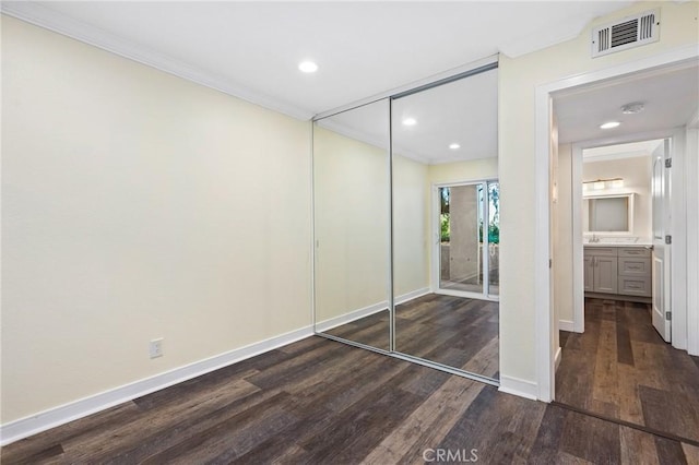 unfurnished bedroom with sink, crown molding, a closet, and dark hardwood / wood-style flooring