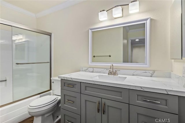 full bathroom featuring toilet, combined bath / shower with glass door, hardwood / wood-style flooring, crown molding, and vanity