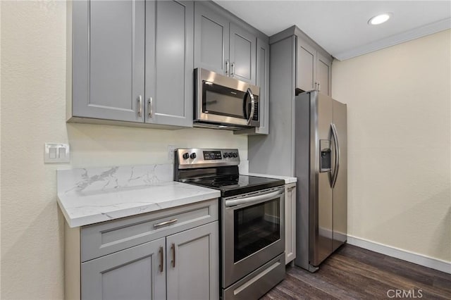 kitchen featuring appliances with stainless steel finishes, gray cabinetry, dark hardwood / wood-style floors, and light stone countertops