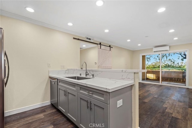 kitchen with light stone countertops, stainless steel appliances, sink, kitchen peninsula, and a barn door