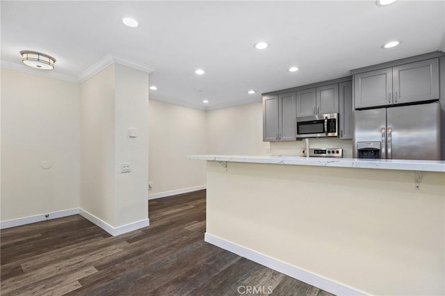 kitchen with a breakfast bar area, stainless steel appliances, gray cabinetry, dark hardwood / wood-style flooring, and crown molding