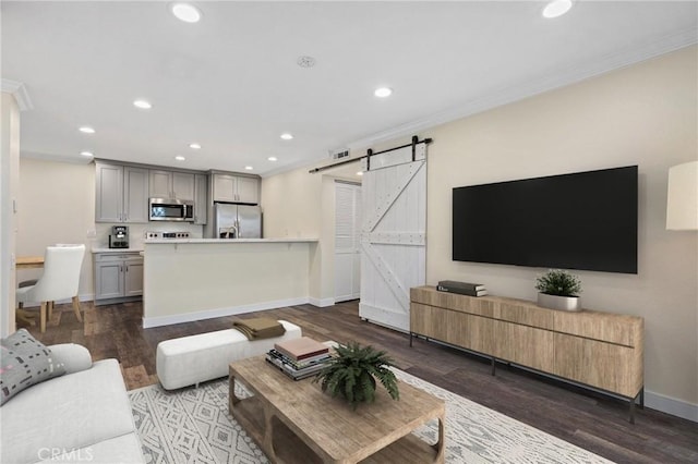 living room with a barn door, dark hardwood / wood-style flooring, and ornamental molding