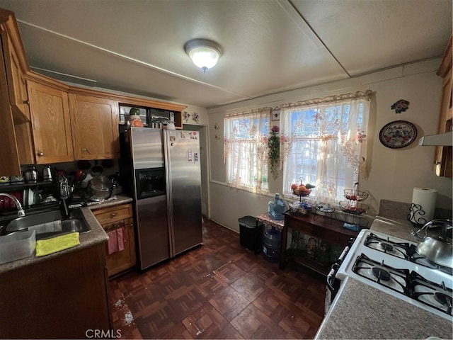 kitchen with gas range, sink, stainless steel fridge with ice dispenser, and dark parquet floors