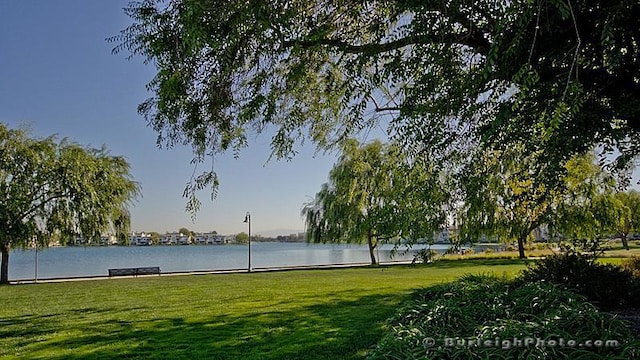 view of property's community with a lawn and a water view