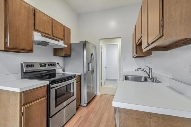 kitchen with stainless steel appliances, sink, and light hardwood / wood-style floors