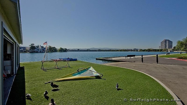 view of home's community with a water view and a yard