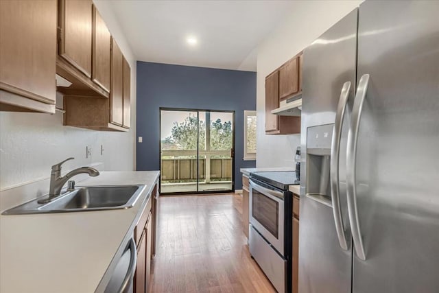 kitchen featuring appliances with stainless steel finishes, sink, and light hardwood / wood-style flooring