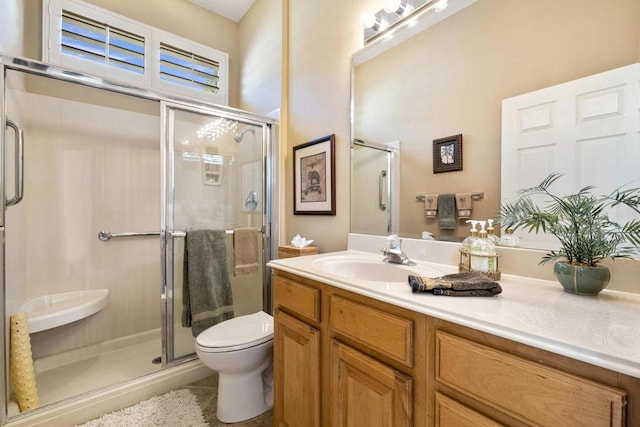 bathroom featuring toilet, vanity, tile patterned floors, and a shower with door