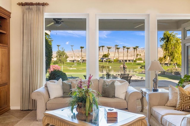 sunroom / solarium with ceiling fan and a water view