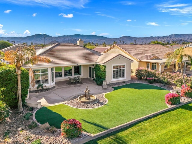 rear view of house with a mountain view, a yard, and a patio