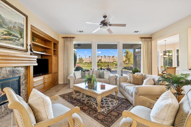 living room with built in features, a fireplace, and ceiling fan with notable chandelier