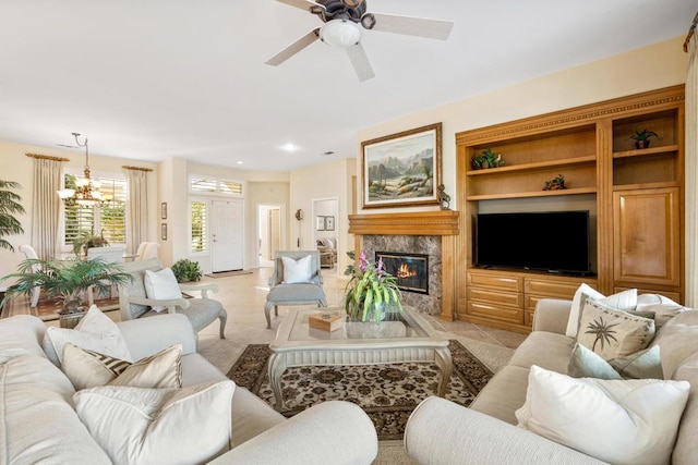 living room with a premium fireplace, light tile patterned floors, and ceiling fan with notable chandelier