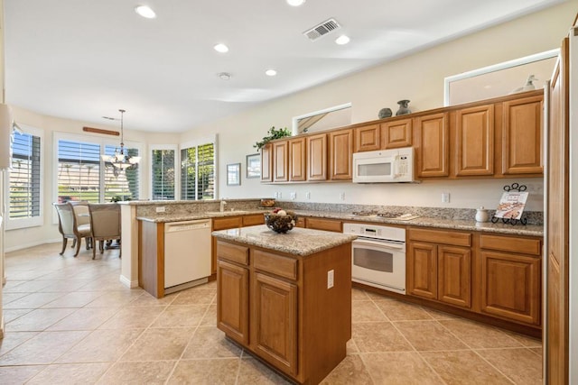 kitchen featuring kitchen peninsula, white appliances, a chandelier, pendant lighting, and a center island