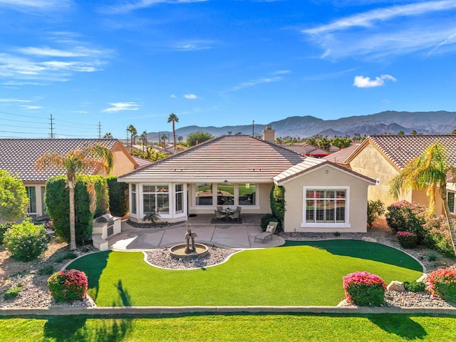 back of house featuring a lawn, a patio area, and a mountain view