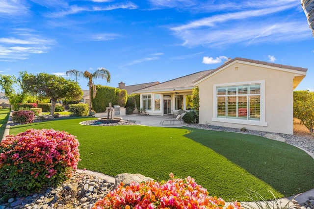 rear view of house featuring a lawn and a patio