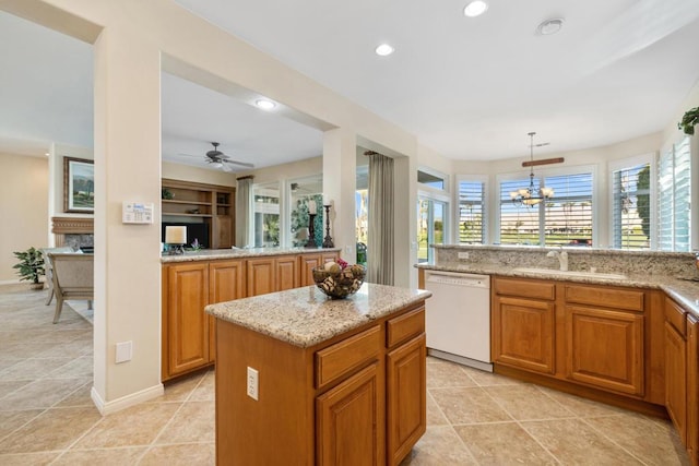 kitchen with sink, dishwasher, pendant lighting, light stone counters, and a center island