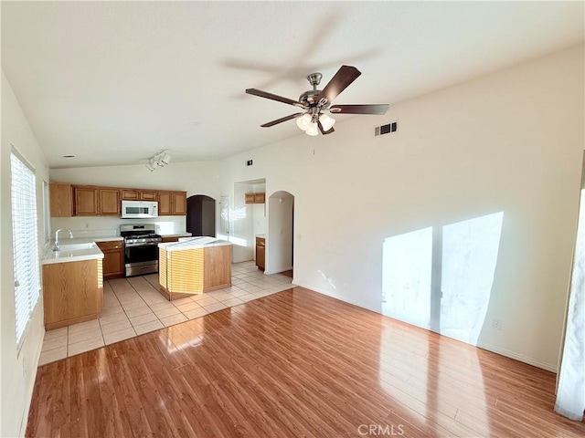 kitchen featuring stainless steel range, vaulted ceiling, light hardwood / wood-style floors, and sink