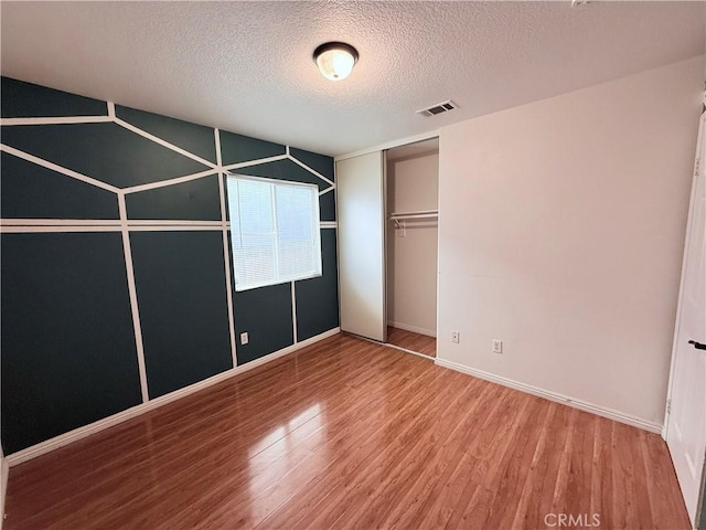 unfurnished bedroom featuring wood-type flooring, a closet, and a textured ceiling