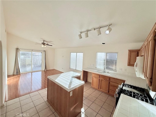 kitchen featuring sink, light tile patterned floors, tile countertops, and a kitchen island