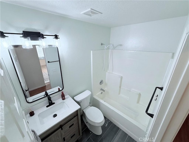 full bathroom featuring a textured ceiling, shower / tub combination, vanity, and toilet