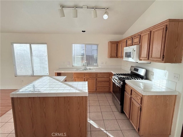 kitchen with light tile patterned flooring, tile countertops, sink, and stainless steel gas range oven