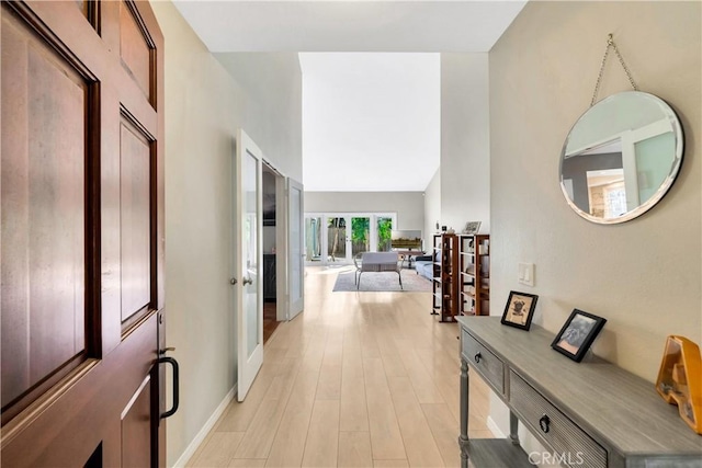 corridor with baseboards and light wood-style flooring