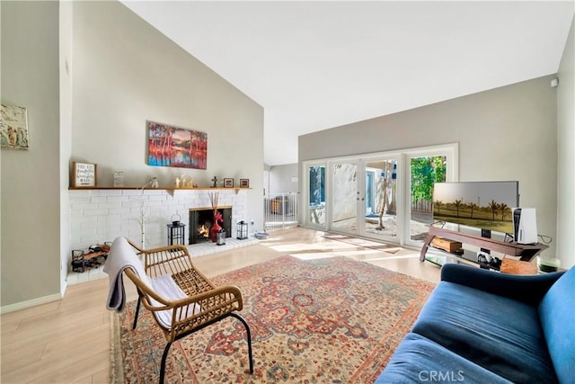 living room featuring french doors, a brick fireplace, high vaulted ceiling, and light hardwood / wood-style flooring