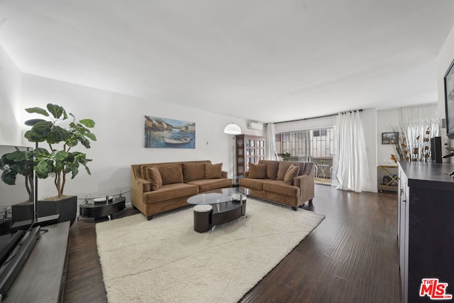 living room featuring an AC wall unit and dark hardwood / wood-style flooring