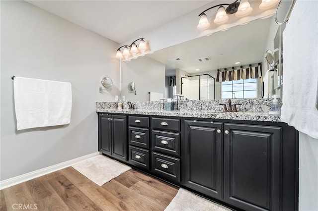 bathroom with hardwood / wood-style flooring, walk in shower, and vanity