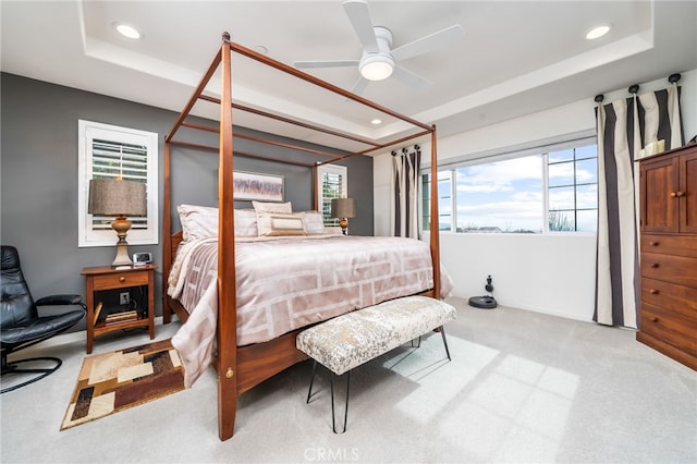 bedroom featuring ceiling fan, light carpet, and a tray ceiling