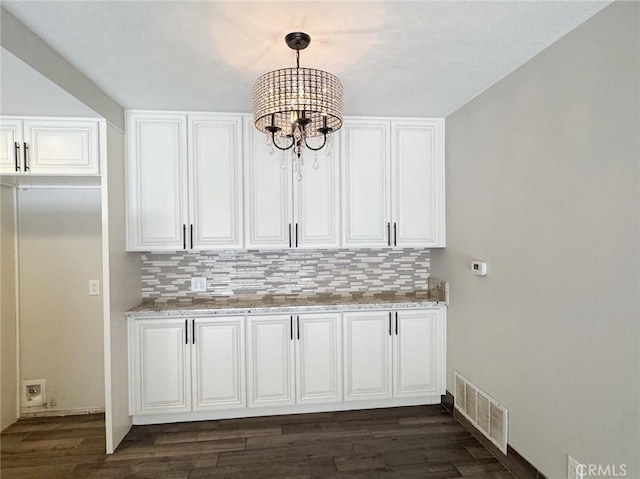 kitchen featuring white cabinetry, tasteful backsplash, a notable chandelier, pendant lighting, and light stone counters