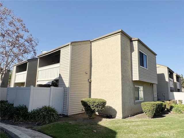 view of side of home with a balcony and a yard