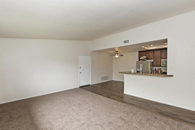 unfurnished living room with ceiling fan and dark carpet