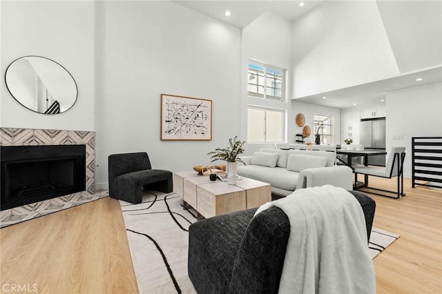 living room featuring a fireplace, a high ceiling, and light hardwood / wood-style flooring