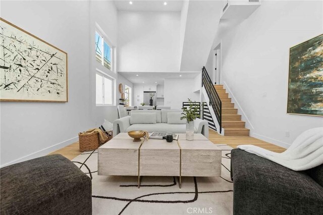 living room featuring light wood-type flooring and a towering ceiling