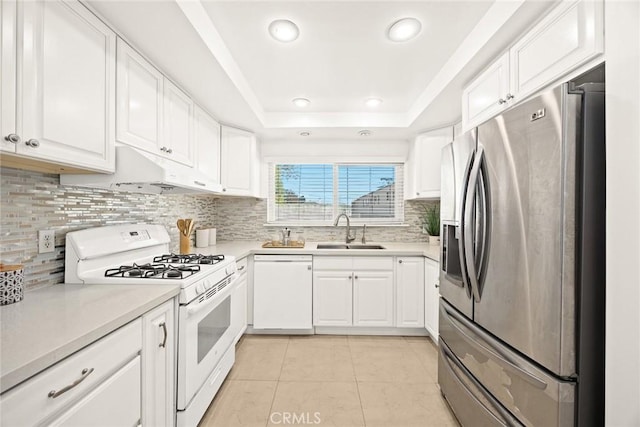 kitchen featuring a tray ceiling, sink, white appliances, and white cabinets