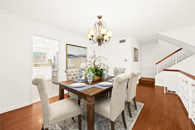 dining area featuring dark hardwood / wood-style flooring, sink, a chandelier, and ornamental molding