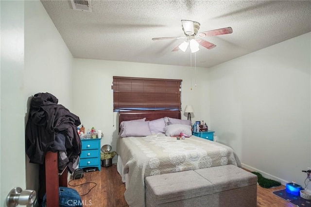 bedroom with a textured ceiling, ceiling fan, and dark hardwood / wood-style floors