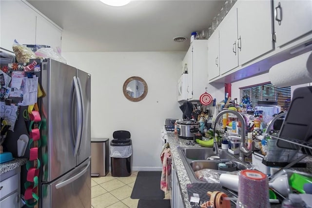 kitchen featuring light tile patterned floors, sink, white cabinets, and stainless steel fridge