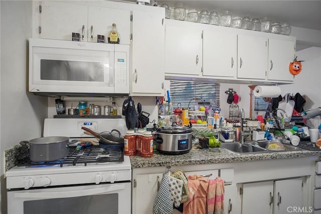 kitchen with white cabinets, sink, and white appliances