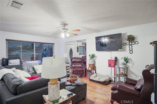 living room featuring ceiling fan, wood-type flooring, and a textured ceiling