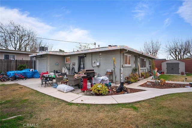 rear view of property with cooling unit, a storage unit, a yard, and a garage