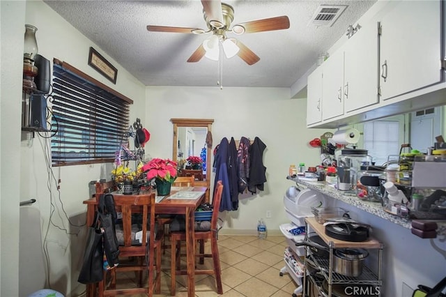 kitchen with ceiling fan, light tile patterned flooring, white cabinetry, and a textured ceiling