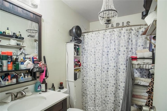 bathroom with toilet, vanity, an inviting chandelier, and a shower with shower curtain