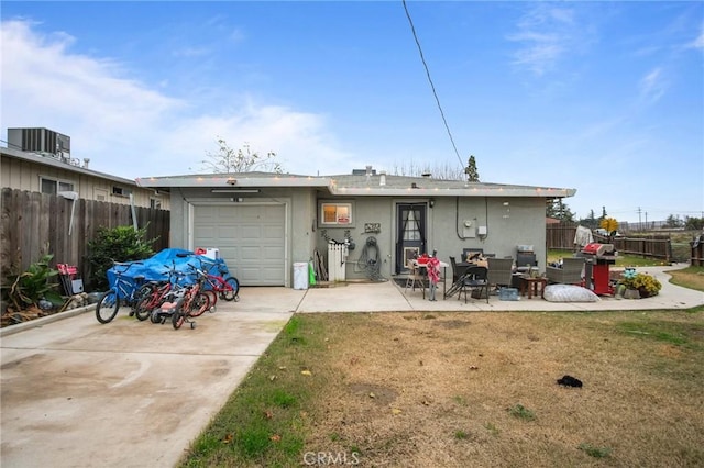 back of property featuring a garage, a patio area, a lawn, and central AC