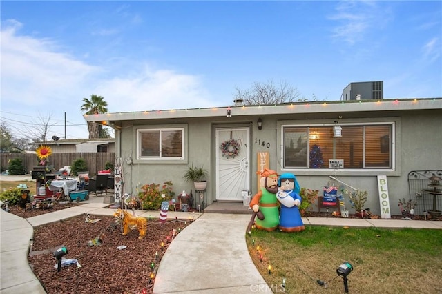 view of front of home with a front lawn and central AC